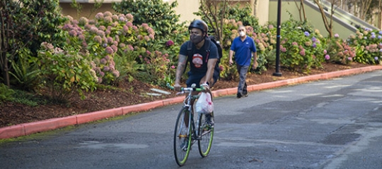 Student biking at SFSU wearing mask